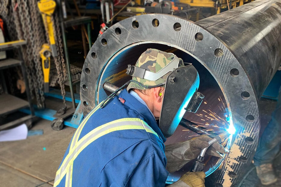 A male worker welding a large steel pipe